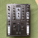 Černý DJ kontroler s nápisem TRAKTOR KONTROL Z2 a logem NI v pravém horním rohu. Zařízení obsahuje dva kanály s knoflíky Gain, Mid a Low, faderem hla…