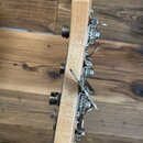 Detail hlavy kytary z jasného dřeva s viditelnou strukturou slátek. Na zadní straně jsou umístěny čtyři kovové ladicí mechanismy stříbrné barvy. Nást…