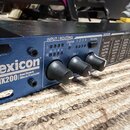Modrý rackový efektový procesor s nápisem Lexicon MX200 Dual Reverb Effects Processor. Na předním panelu jsou tři černé otočné ovladače a sekce INPUT…