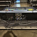 Digitální mixovací pult v černé barvě s ovládacími prvky na horní straně. Na zadní části je viditelné bílé logo MIDAS a štítek s nápisem LF0589. Do z…