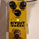 Žlutý kytarový efekt s nápisem RIVULET CHORUS. Na horní straně jsou tři černé otočné knoflíky s popisy RATE, WIDTH a INTENSITY. Uprostřed svítí zelen…