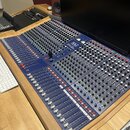 Velký mixovací pult s modrým povrchem a dřevěným rámem. Na přední straně je viditelné logo R.A.C a nápis 1604-USB. Přístroj obsahuje velké množství p…
