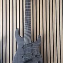 Šedá elektrická kytara s tmavým hnedým povrchem a viditelnou strukturou dřeva. Na hlavě je bílý nápis LTD Deluxe. Nástroj má dva humbuckery, jeden ov…