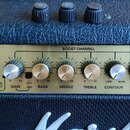 Detail kytarového zesilovače značky Marshall. Zlatý ovládací panel obsahuje nápisy BOOST CHANNEL, GAIN, BASS, MIDDLE, TREBLE a CONTOUR s doprovodnými…