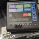 Černý procesor vokalových efektů s dotykovým displejem. V horní části je nápis TC HELICON a model VOICELIVE Touch. Na displeji jsou vidět tlačítka s…