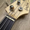 Detail hlavy basové kytary z přírodního dřeva s černým hрифem. Na hlavě je čitelně napsáno logo Harley Benton a nápis Standard Series. Jsou vidět čty…