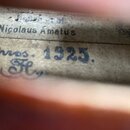 Detailní pohled na vnitřní štítek smyčcového nástroje. Na štítku je tištěný nápis Nicolaus Amatus a pod ním ručně psaný modrý text včítějící rok 1925…