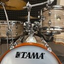 Bubnová sada značky TAMA v dřevěném provedení s viditnou strukturou zrna. Na basovém bubnu je výrazné černé logo TAMA. Soubor obsahuje snare, tom a b…