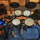 Elektronická bicí souprava značky Roland s černými pady a černé činely. Na bílých plochách padů jsou viditelné loga Roland a nápisy V-Drums. Součástí…