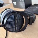 Černé sluchátka s šedými velkými náušníky. Na vnější straně náušníku je bílý nápis DT 990 PRO 250 OHM a na náhlavním oblouku nápis beyerdynamic L. V…