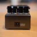 Zadní strana šedého kytarového efektu s kovovým povrchem. Na zadní straně je vstup pro napájení a nápis USE BOSS PSA ADAPTOR ONLY 9V s grafickým ozna…