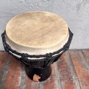 Černý djembe s hnědou koženou blánou. Okraj je zajištěn černým pleteným provázkem. Na spodní části korpusu je viditelné opotřebení a odloupaná barva.…
