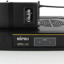 Černý bezdrátový přijímač s nápisem MIPRO a označením MR-801 a UHF TRUE DIVERSITY RECEIVER. Na přístroji je umístěn černý vysílač s nápisem MIPRO MT-…