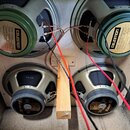 Fotografie zachycuje čtyři reproduktory značky CELESTION namontované v dřevěné skříni. Horní dva mají zelený rám a nápisy Model number G12 M Greenbac…