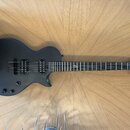 Černá elektrická kytara s matným povrchem a dvěma humbuckery. Na hlavě hředu je bílý nápis "Yamaha". Hриф obsahuje jeden viditelný znak vtíraný do hm…