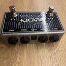 Stříbrný kytarový pedál s černým horním panelem a dvěma kovovými spínači. Na panelu je bílý nápis SWITCH BLADE+ a logo Electro-Harmonix NEW YORK CITY…