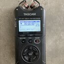 Černý digitální nahrávač značky TASCAM s označením DR-40X Linear PCM RECORDER. Zařízení má zapnutý displej, na kterém je vidět text FOLDER 0062/0069…