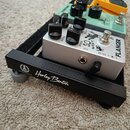 Na černé pedalboardu značky Harley Benton jsou umístěny tři efektové pedály. V popředí je stříbrný pedal s nápisy FLANGER, SO WHAT a SPEED. Za ním ná…