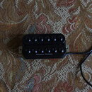 Černý humbucker s dvěma řadami šesti magnetických pólů. Na spodní části je bílý nápis Seymour Duncan. K snímači vede černý kabel.
