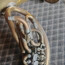 Detailní záběr na mosazný saxofon s matným povrchem. Jsou vidět ohyby trubek, spojovací spoje a mechanismus klapek. Na nástroji nejsou žádné čitelné…