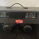 Zadní strana černého kytarového komba s texturovaným povrchem a dvěma reproduktory. Na zadním panelu je nápis Custom, MODEL NO 100FX211 STEREO AMPLIF…