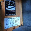 Fotografie detailu zadní strany zesilovače s dvěma nálepkami. Horní černá nálepka nese nápis Marble amps, Designed and handwired in The Netherlands a…