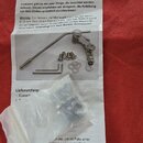 Fotografie zobrazuje sadu komponentů pro kytarové tremolo umístěnou na bílém informačním letáku. Na papíře je vidět logo a nápisy DUESENBERG Les Trem…