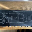 Černý šestikanálový sluchátkový zesilovač s bílým technickým schématem na horní straně. Na šasi je nápis PROFESSIONAL SIX CHANNEL HEADPHONE AMPLIFIER…