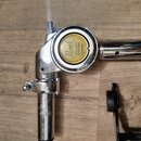 Detail chromovaného kovového spojovacího mechanismu s nápisem Pearl UNI-LOCK SYSTEM PATENTED na žlutém kulatém prvku. Součásti jsou v lesklém stavu s…