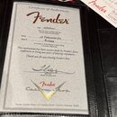 Fotografie zachycení certifikátu pravosti (Certificate of Authenticity) značky Fender v černé kožené bindru. Dokument obsahuje text „Model 50 Telecas…
