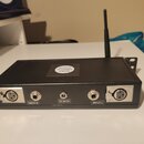 Černý obdélníkový box s anténou, který slouží jako bezdrátový systém. Na horní straně je nálepka s nápisem ROCKY WIRELESS SYSTEM. Přední panel obsahu…