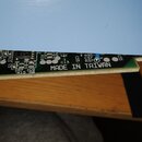 Detailní záběr na hranu zelené printed circuit board (PCB) s osazenými elektronickými součástkami. Na desce je bílým tiskem nápis MADE IN TAIWAN a oz…