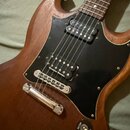 Hnědá elektrická kytara s přírodním dřevem a černým pickguardem. Na hradle je vidět nápis seymour Duncan u jednoho z útoňů. Kytara má chromovaný most…