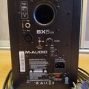 Zadní strana černého studiového monitoru značky M-AUDIO, model BX5 D3. Jsou zde vidět vstupy TRS a XLR, ovládací prvky pro VOLUME a ACOUSTIC SPACE (n…