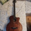 Akustická kytara s hnědým dřevěným povrchem a výřezem v těle. U otvoru je viditelné logo „Leko“ a pod ním nápis „Guitar“. Nástroj je v dobrém stavdu…