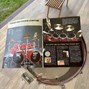Fotografie zachicuje otevřený katalog s reklamou na červenou bicí sadu. V textu je vidět nápis POWER RECORDING CUSTOM a logo YAMAHA na basových bubne…