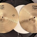 Dvě mosazné činely typu hi-hat s koncentrickým broušením. Na obou je viditelné logo paiste Twenty a nápis TRADE MARK MADE IN SWITZERLAND. Levý činel…