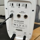 Zadní strana bílého studiového reproduktoru značky ADAM AUDIO, model D3V: LEFT LOUDSPEAKER. Na zadním panelu jsou tři přepínače s nápisy POSITION (ST…