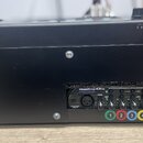 Černý rackový šasi, v němž je osazen sluchátkový zesilovač s nápisem HeadAmp 4 Pro Five Channel Headphone Amp with Listen and Talkback. Na zařízení j…