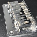 Chromovaný most k elektrické kytáře s pěti sedly. Povrch vykazuje známky opotřebení, jsou vidět drobné škrábance a znečištění. Na komponentu nejsou v…