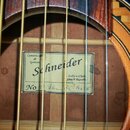 Detail vnitřku akustické kytary s viditelnou štítkovou nálepkou. Na nálepce je uveden text: Constructor de Guitare Schneider, Luby u Chebu Czech Repu…