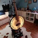 Na fotografii je hybridní nástroj kombinující kontrabas a buben. Na bílém bubnovém povrchu je černý nápis „Country music session Kontrabass Banjo“. N…