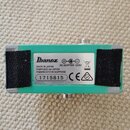 Spodní strana zeleného kytarového efektu s dvěma černými suchými plátny. Na bílém štítku je logo Ibanez, nápisy MADE IN JAPAN, FABRIQUÉ AU JAPON, FAB…
