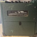 Zadní strana zeleného kytarového komba s texturovaným povrchem. Na černé zadní štítku jsou uvedeny údaje Model No. MINIS-RM a Serial No.. 711115, dál…