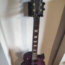 Fialová elektrická kytara s tmavým hnedým hmatníkem. Na hlavě je zlatý nápis Gibson a na zadní straně hmatníku nápis LPJ. Kytara má dva humbuckery, č…