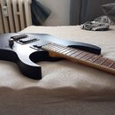 Černá elektrická kytara s tmavým hnedým hmatníkem. Na těle jsou dva humbuckery, jeden ovládací knoflík a přepínač. Povrch těla vykazuje drobné škrába…