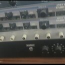 Svrhátě jsou zobrazeny čtyři rackové jednotky v kovovém provedení. Horní dvě stříbrné jednotky mají nápis APHEX SYSTEMS LTD STUDIO DOMINATOR. Třetí j…