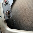 Detail vnitřní části nástroje s viditelným kusem elektroniky a dvěma pájkovanými spoji. Na vnitřní dřevěné stěně je vyražené číslo 003. Povrch kovu a…