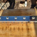Kovový efektový pedalboard stříbrné barvy s pětmi stoupacími spínači. Na levém a pravém okraku je svisle napsán nápis SMASHNEFFECTS. Pod spínači jsou…