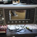 Šedý rackový digitální mixér s nápisem behringer X32 RACK POWERED BY MIDAS. Zařízení má centrální displej, několik ovládacích tlačítek a pět otočných…